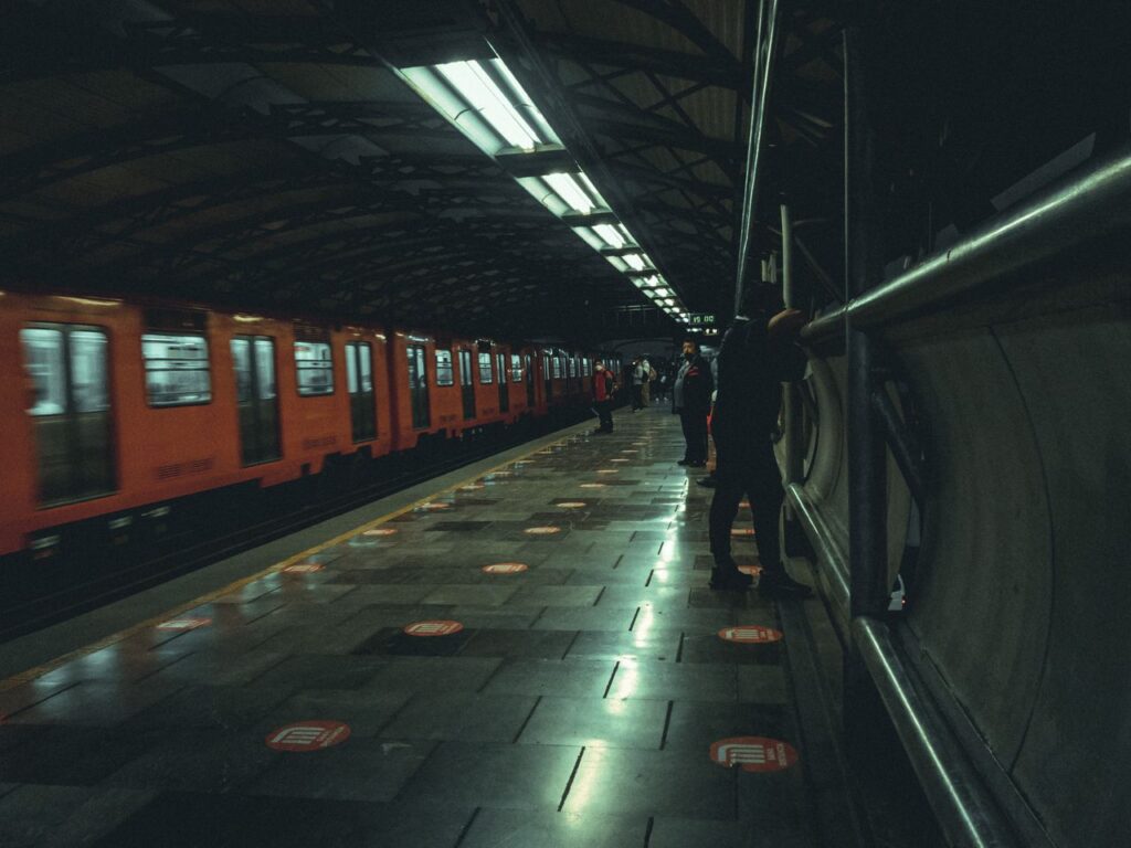 Orange trains in a bustling Mexico City subway station at night, capturing urban life.